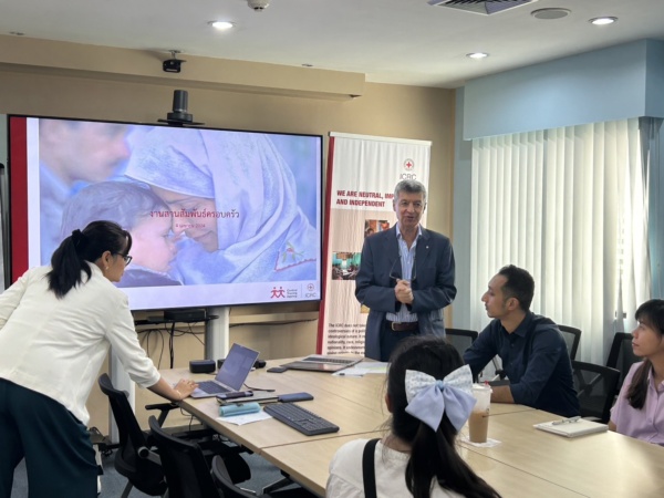 S__72957989 บุคคล 5 คนในห้องประชุมโดยมีผู้ชายยืนพูดอยู่หน้าห้อง