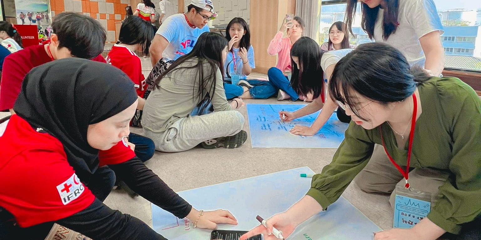 กลุ่มคนกำลังทำกิจกรรมโดยการเขียนบนกระดาษขนาดใหญ่