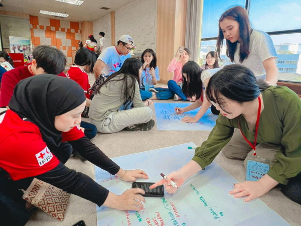 กลุ่มคนกำลังทำกิจกรรมโดยการเขียนบนกระดาษขนาดใหญ่