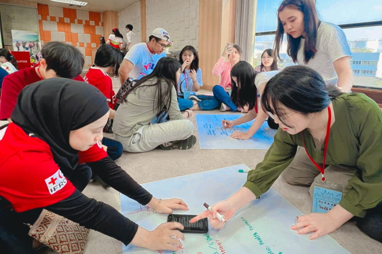 กลุ่มคนกำลังทำกิจกรรมโดยการเขียนบนกระดาษขนาดใหญ่